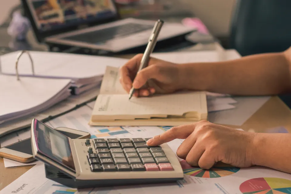 Mains utilisant une calculatrice au-dessus de documents budgétaires
